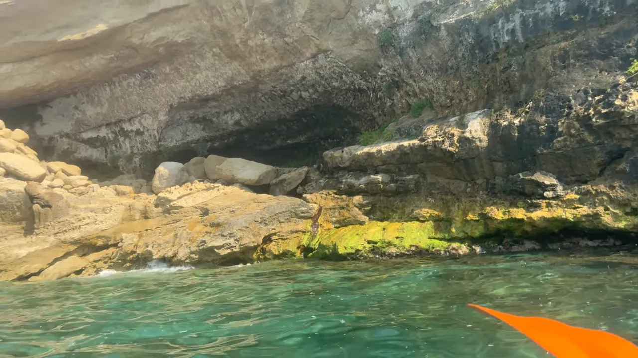 Vista dalla canoa della costa rocciosa di Pizzo con una pagaia arancione in primo piano