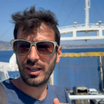 primo piano di un uomo che parla sul ponte di un traghetto, gesto esplicativo