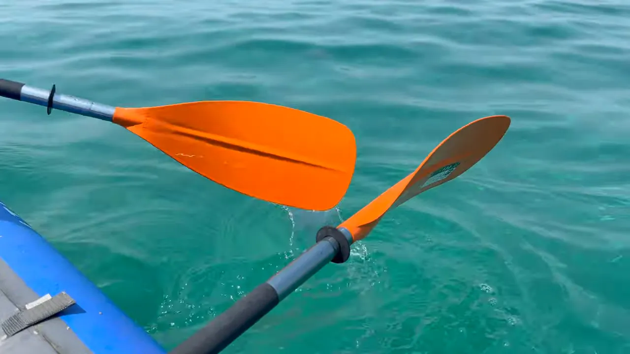 Due pale di remo arancioni su un kayak che sfiorano il mare turchese
