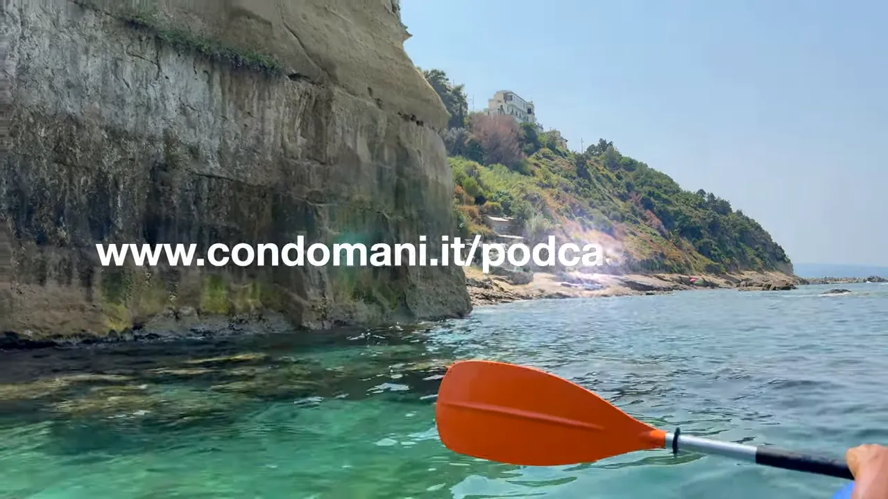 pagaia arancione a bordo di un kayak con scogliera e mare limpido