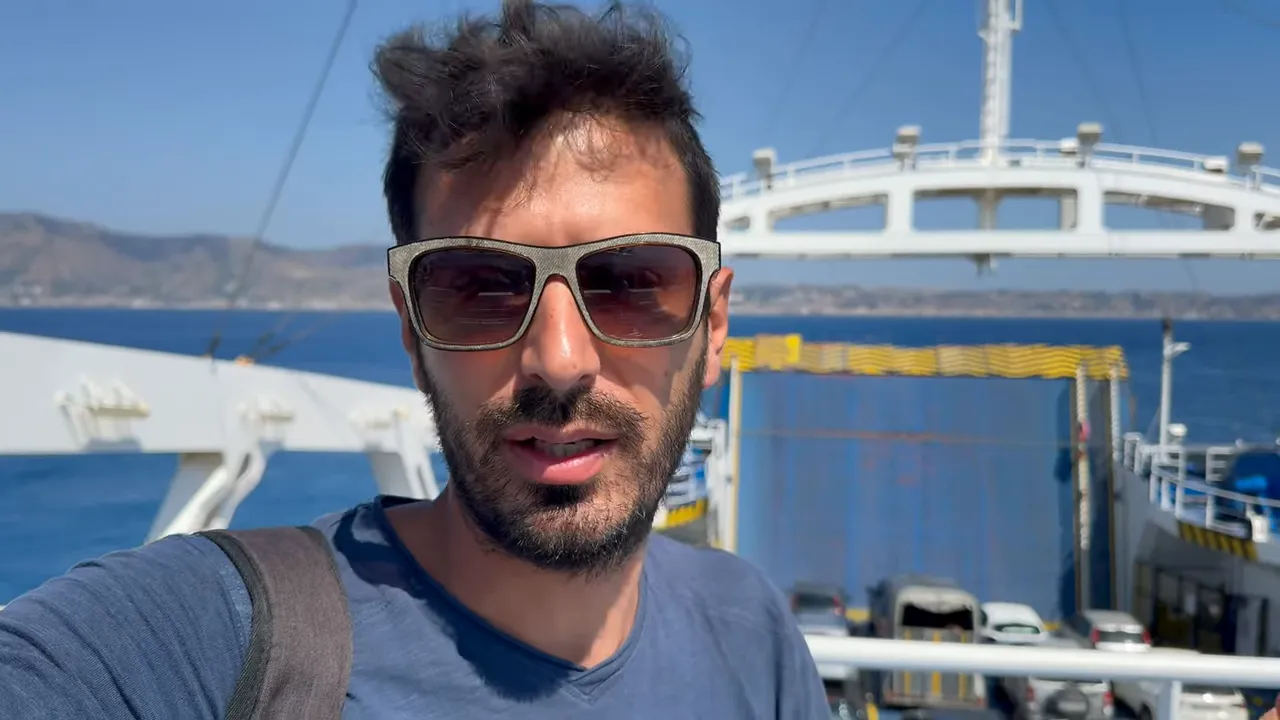 persona con occhiali da sole sul ponte di un traghetto con auto e mare sullo sfondo