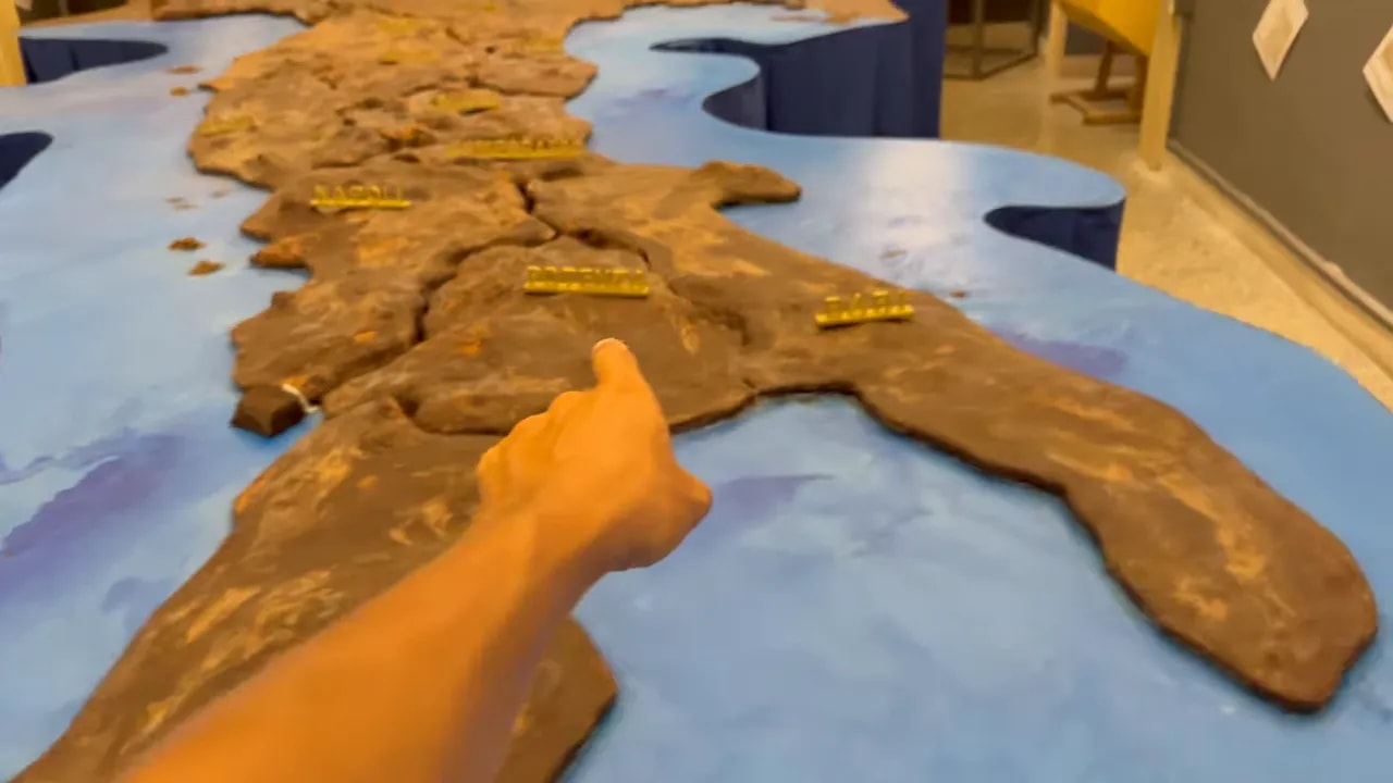 mano che indica la mappa in miniatura dell'italia esposta al museo